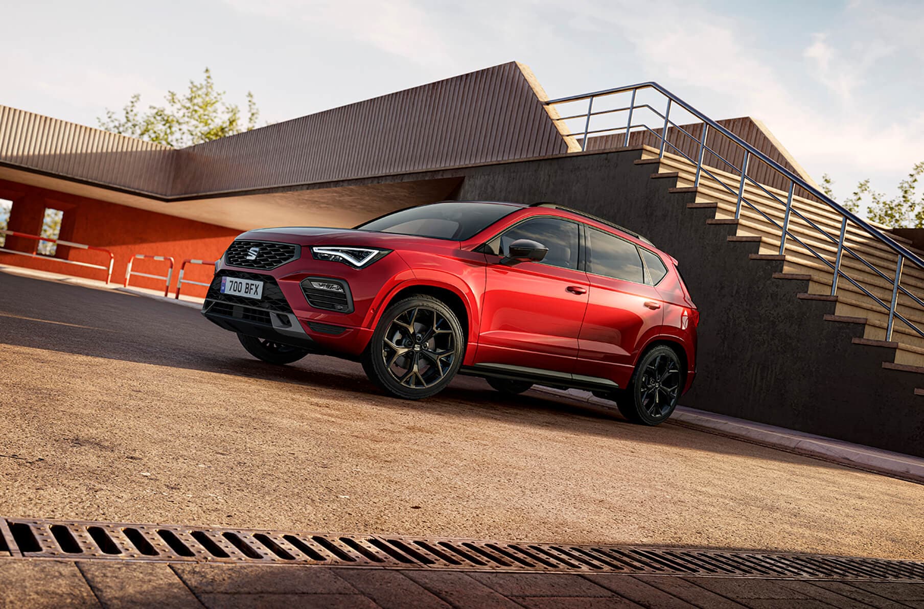Glossy black mirror covers for the seat leon fr contrasting with the red car body, side view with cement background.