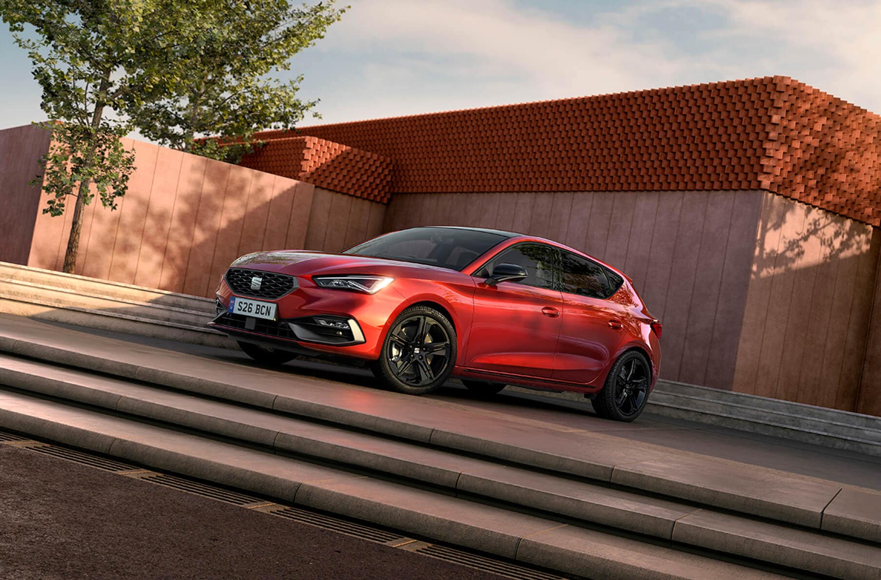 Glossy black mirror covers for the seat leon fr contrasting with the red car body, side view with cement background.