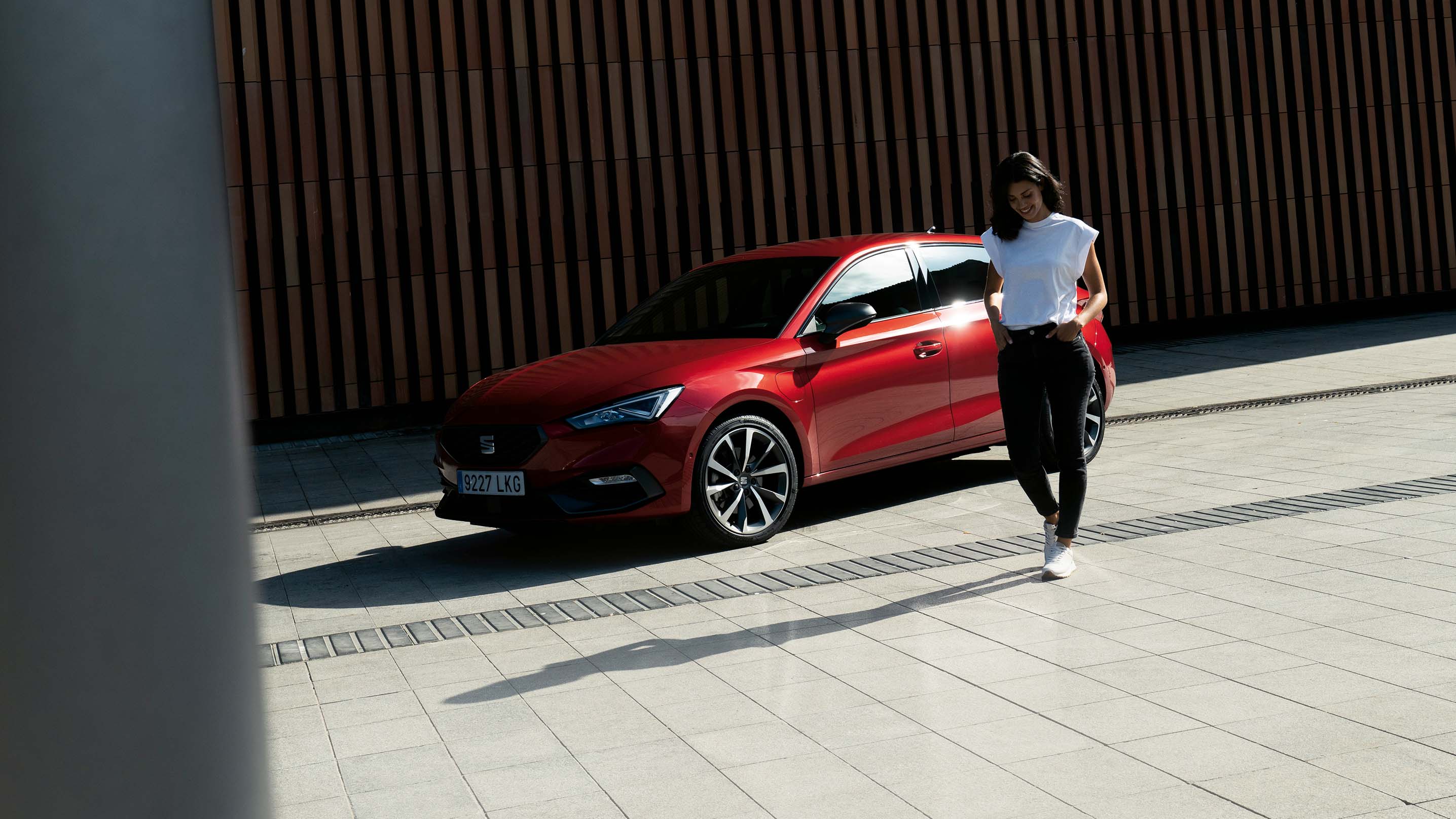 A woman smiling whilst walking away from her new red SEAT Leon
